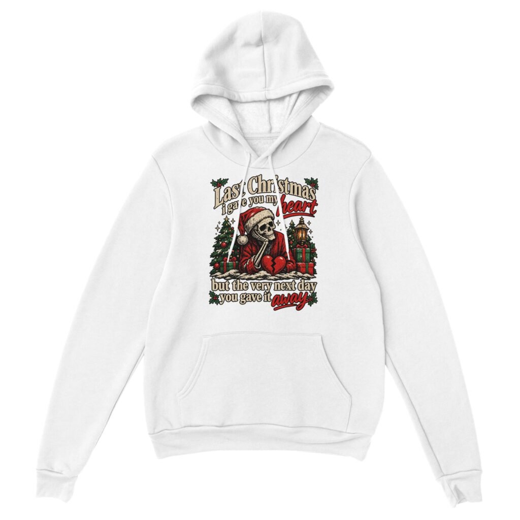 White skeleton christmas hoodie with a skeleton in a Santa hat resting its chin on its hand beside a broken red heart, with Christmas trees, gifts, a lantern and cream and red lettering